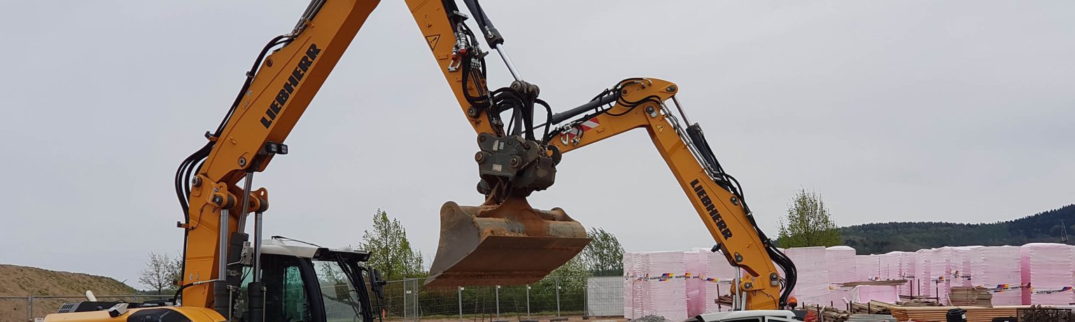 Zwei Bagger in einer Baugrube mit Dämmmaterial im Hintergrund