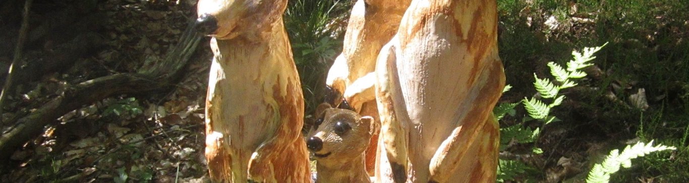 Geschnitzte Erdmännchen auf einem Baumstamm