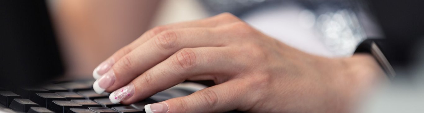 Elegant manikürte Damenhand auf einer Tastatur