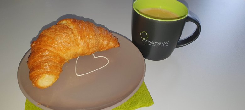 Die Linsengericht-Tasse mit Gemeindelogo, daneben ein Teiller mit einem Croissant