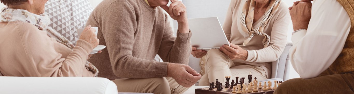 Senioren, die in einem gemütlichen Wohnzimmer Schach spielen